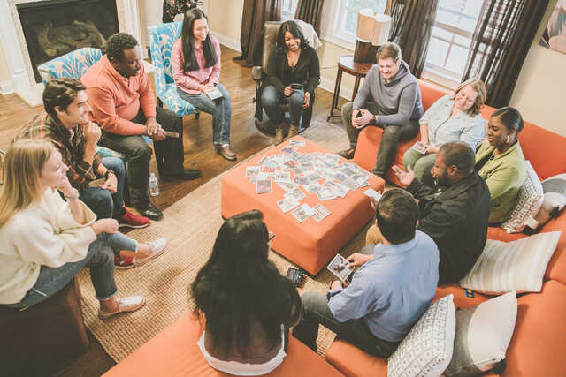 community group members sitting in a living room with conversation cards