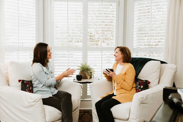 women having a lighthearted discussion over coffee in a living room
